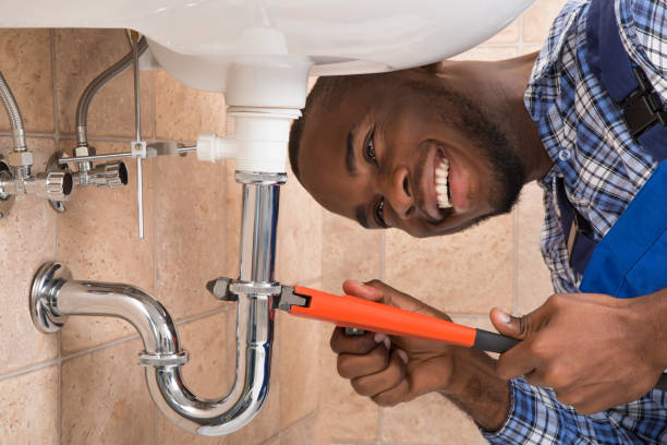 Close-up Of Happy Young African Male Plumber Repairing Sink In Bathroom